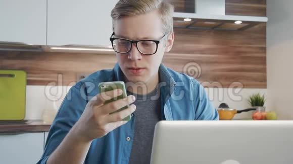 使用笔记本电脑和智能手机在家庭办公室工作的年轻人视频的预览图