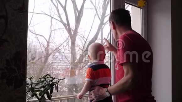 一位老人和他可爱的小孙子在窗边玩耍爷爷给小男孩看了一只鸟视频的预览图