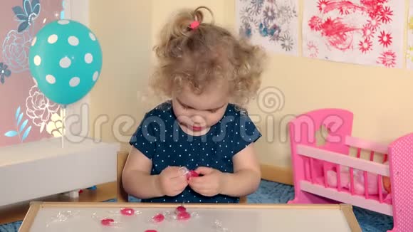 可爱的女孩把糖果糖果从纸上拿出来品尝视频的预览图