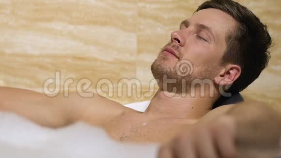 英俊的男性躺在浴缸里享受愉快的时光冥想和休闲视频的预览图