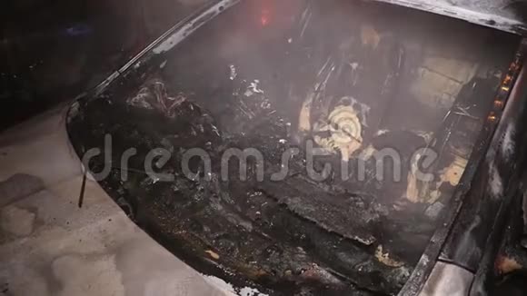 一辆汽车在城市街上着火一名男子试图用灭火器灭火但完全烧毁了室内视频的预览图