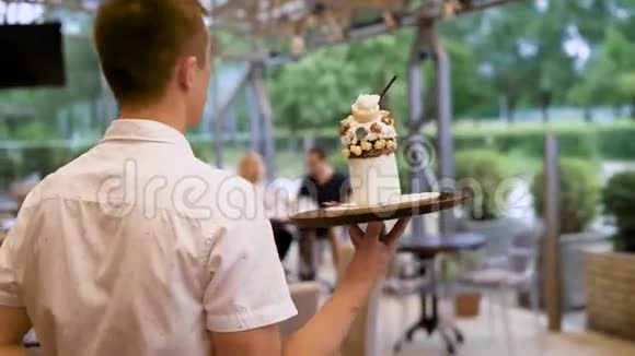 热情好客的服务员走到桌子前给小客户带来美味的甜点和鲜奶油和巧克力快乐视频的预览图