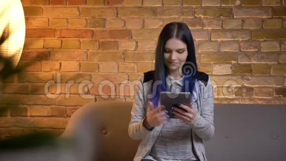 用平板电脑拍摄染发的年轻漂亮白种人女性的特写镜头并用绿色屏幕拍摄视频的预览图