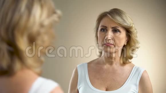 退休女性摸着她的脸思考整容手术反思视频的预览图