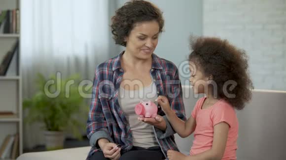 妈妈和女儿把硬币扔进储蓄罐存钱送礼物视频的预览图