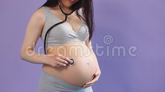 孕妇用听诊器听她的肚子闭上眼睛视频的预览图