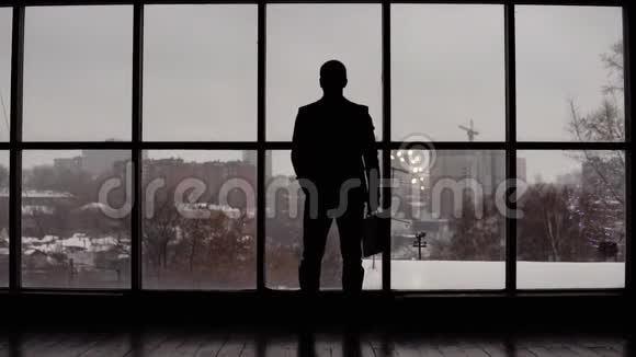 商人在靠窗的办公室里用手表看时间视频的预览图