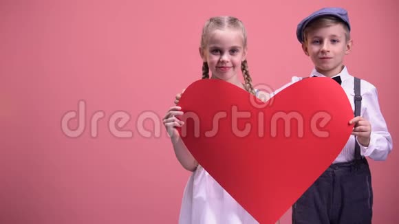 两个浪漫的孩子躲在红心剪贴画后面接吻初恋视频的预览图