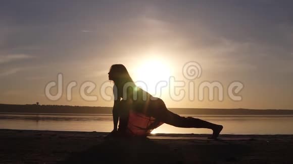 美丽的瑜伽女人的剪影在清晨的天空中在一个海边一个练习瑜伽的女人维拉巴德拉萨纳二世勇士视频的预览图