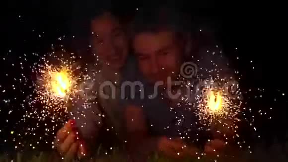 快乐的年轻夫妇晚上拿着燃烧的火花超级慢动作500f视频的预览图