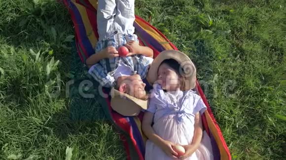 快乐的孩子戴着草帽躺在毯子上手里拿着苹果在夏天交流视频的预览图
