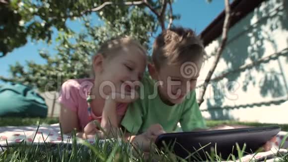 快乐的孩子在花园里看平板电脑视频的预览图