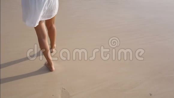 女人的腿在沙滩上留下脚印挥手洗去脚印视频的预览图