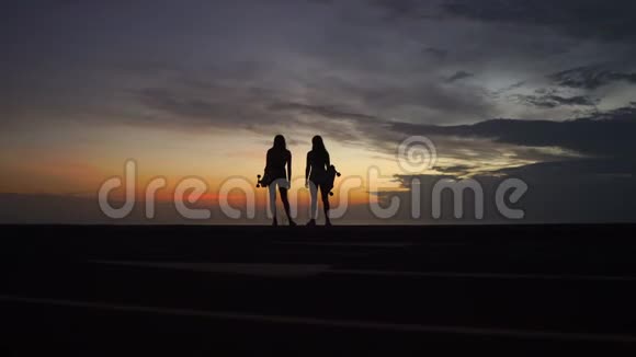 女朋友在山顶上玩滑板后看日落的美丽景色视频的预览图
