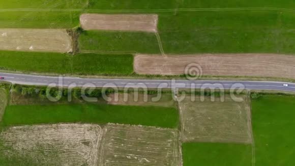 空中无人机镜头两辆车在田野之间的路上行驶视频的预览图