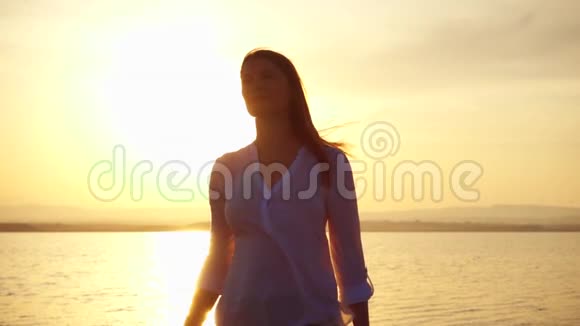 女人在湖边日落时举起手臂女性在黄金时刻缓慢地伸出双手视频的预览图