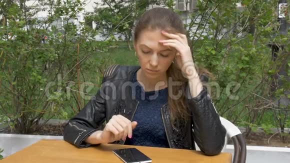 悲伤的漂亮女孩坐在咖啡馆的桌子旁在智能手机上读取短信悲伤和渴望绝望特写视频的预览图
