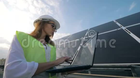 一位漂亮的女士正在太阳能建筑附近操作她的笔记本电脑视频的预览图
