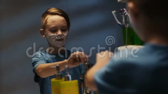 严肃的小男孩在镜子里刮胡子视频的预览图