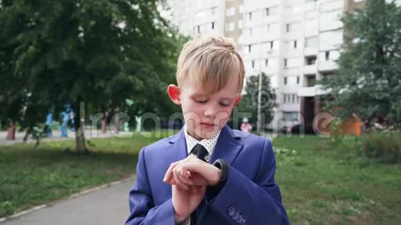 在一个穿着商务服的孩子手上用黑色的表带合上智能手表的特写镜头使用智能手腕视频的预览图