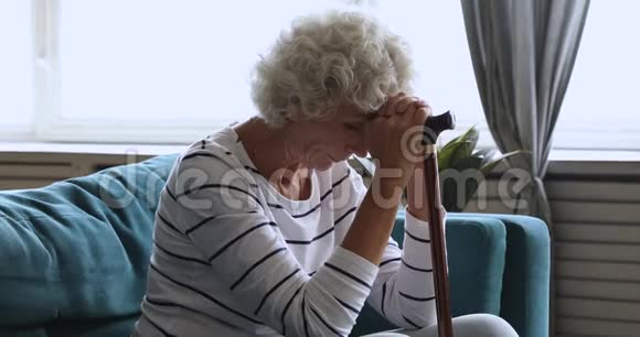 一个孤独的老妇人独自坐在家里拿着拐杖视频的预览图