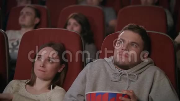 年轻夫妇在电影院看恐怖电影把爆米花洒了视频的预览图