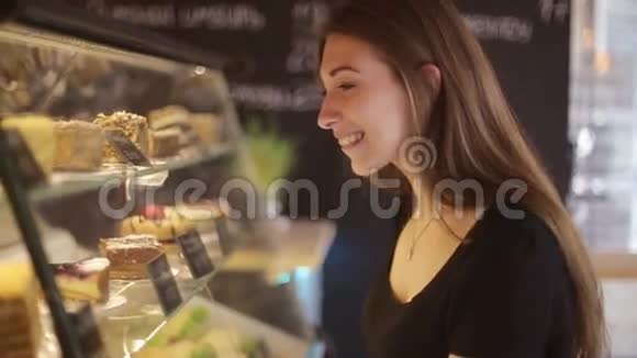 美丽的女性顾客在一家面包店的购物橱窗里指着她正在买的甜点视频的预览图