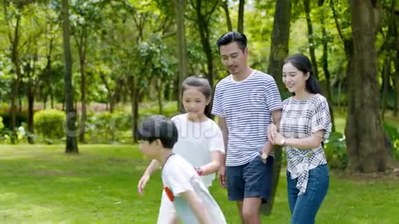 在阳光明媚的夏天4个亚洲家庭在公园里慢动作地散步和欢笑视频的预览图