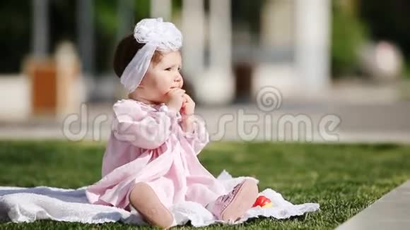 美丽的女婴坐在绿草上在公园里吃烤面包视频的预览图