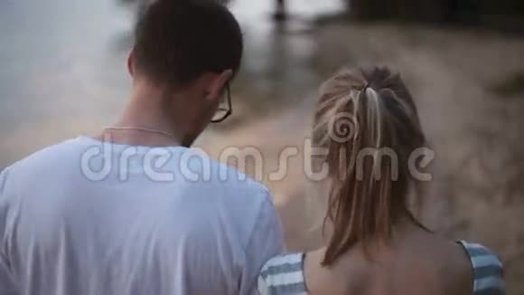 特写后景年轻的情侣日落时沿着湖边散步视频的预览图