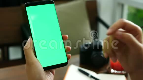 4K镜头在咖啡店用绿色屏幕关闭女士手拿智能手机在手机屏幕上使用手指触摸视频的预览图