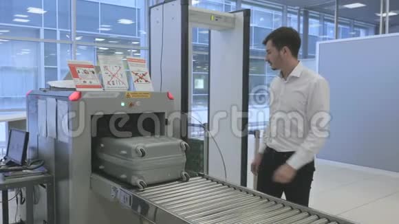 商人在机场用X光扫描仪扫描行李后等待视频的预览图