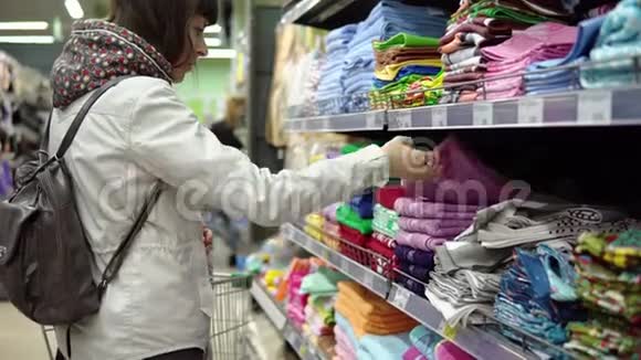 年轻的黑发女人选择和购买特里毛巾在超市视频的预览图