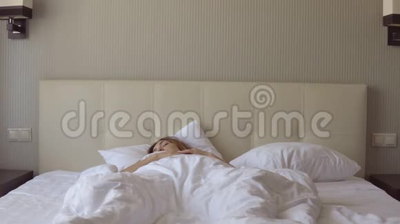 年轻漂亮的困倦女孩突然醒来坐在床上视频的预览图