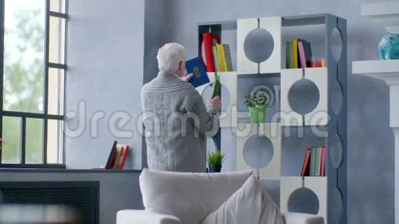 一个老白种人在现代公寓里看书茶视频的预览图
