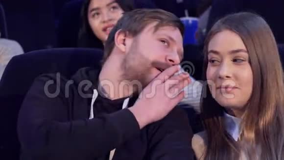 一个男人在电影院跟他的女朋友耳语视频的预览图