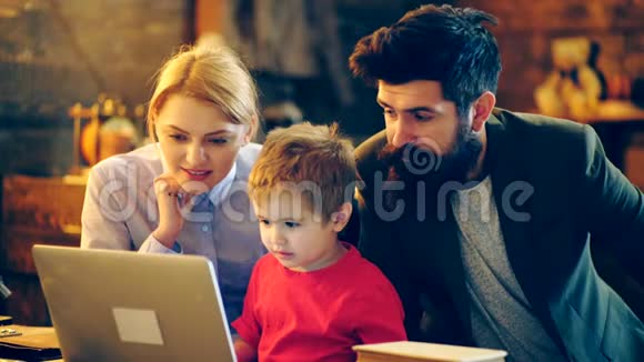 有父母的男孩有兴趣在笔记本电脑上看视频学习观念父母和儿子在家放松视频的预览图
