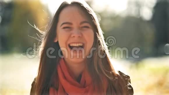 快乐的年轻美丽的女人笑着看着镜头秋天公园的背景十月初秋视频的预览图