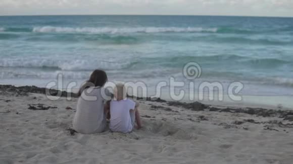 妈妈和儿子坐在海边的海滩上视频的预览图