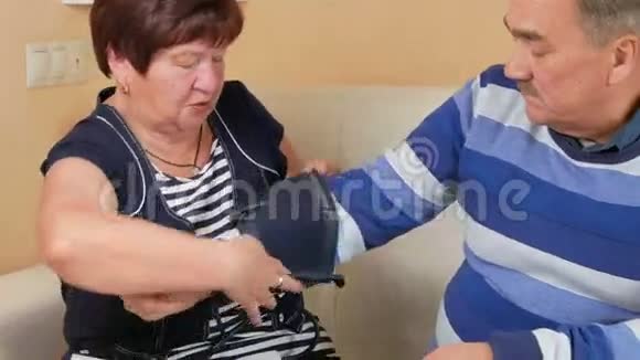 老年妇女在家里在沙发上测量血压穷人的幸福照顾他的妻子视频的预览图