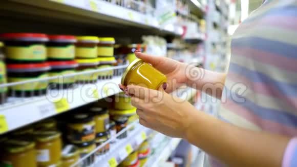 接近白种人的女人手靠近商店货架在杂货店里选择淡蜂蜜视频的预览图