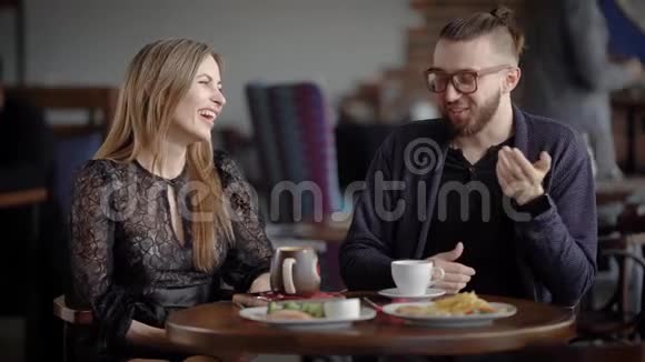可爱的情侣在自助餐厅约会快乐的男人和女人坐在餐桌前吃的和喝的视频的预览图