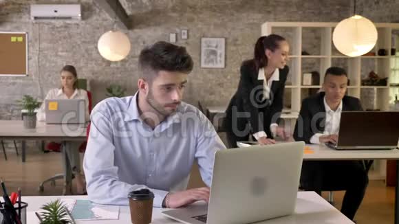 年轻疲惫的商人正在办公室工作手提电脑讨论背景工作理念商业视频的预览图