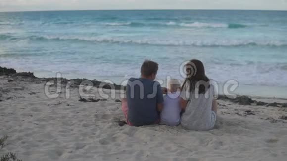 一家人带着孩子坐在海滩上视频的预览图