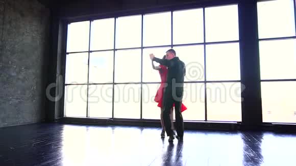 年轻夫妇跳探戈穿红色裙子的职业女孩和跳拉丁舞的男人一个现代化的工作室视频的预览图