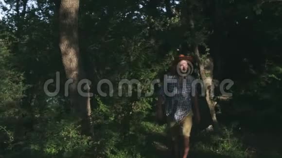 在树林里散步的年轻农民日落时徒步在森林里徒步旅行积极的生活方式穿着格子衬衫视频的预览图