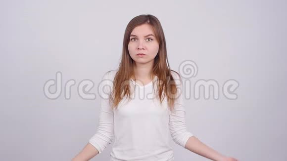 年轻女子在灰色背景下做手势不知道标志视频的预览图