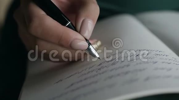 一个女人用钢笔在空笔记本上写手的特写视频的预览图