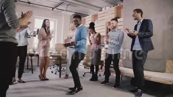 快乐的非裔美国老板和员工在办公室团队建设聚会上跳舞庆祝团队成功慢动作视频的预览图