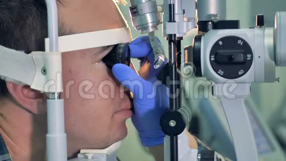 眼科医生双手戴手套用镜片对着病人的眼睛视频的预览图